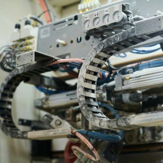 Kabelschleppkette und elektrische Leitungen in einer industriellen Maschinenanlage.